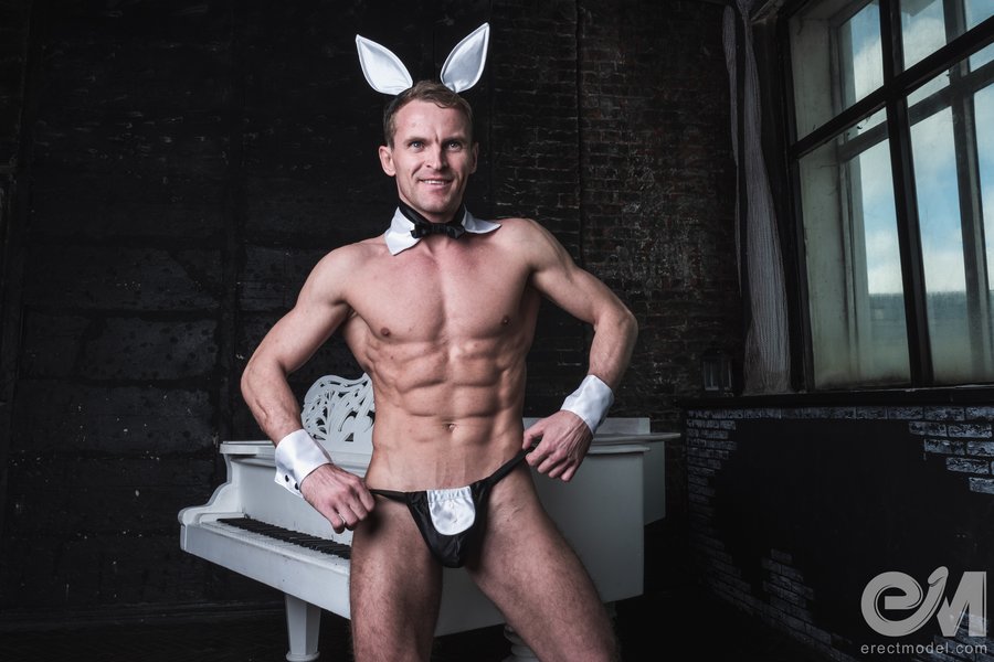 Muscle cock man in bunny suit near the piano